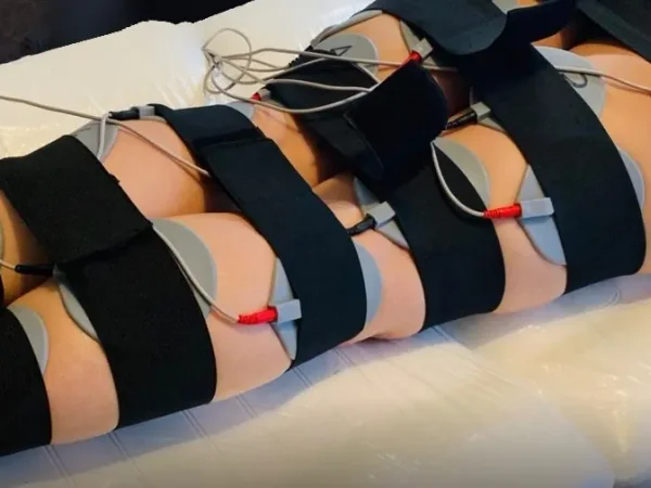 Electrical treatment pads positioned across the thighs and abdomen